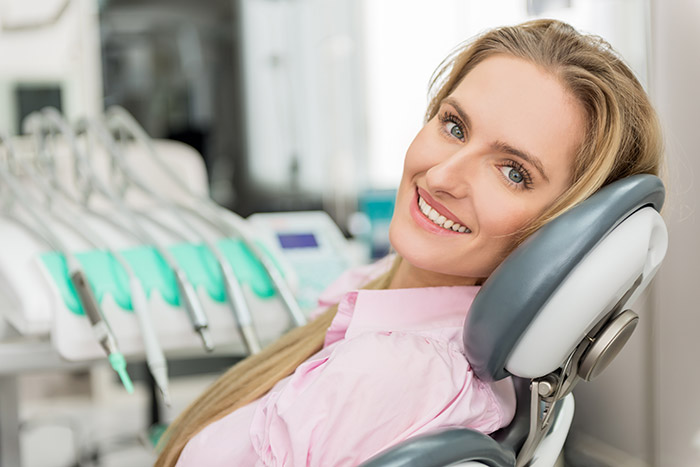 smiling woman in dentist office about to get porcelain veneers