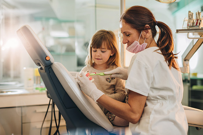 dental hygienist teaching little girl about dental care