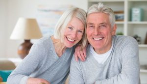 elderly couple in their living room smiling photo