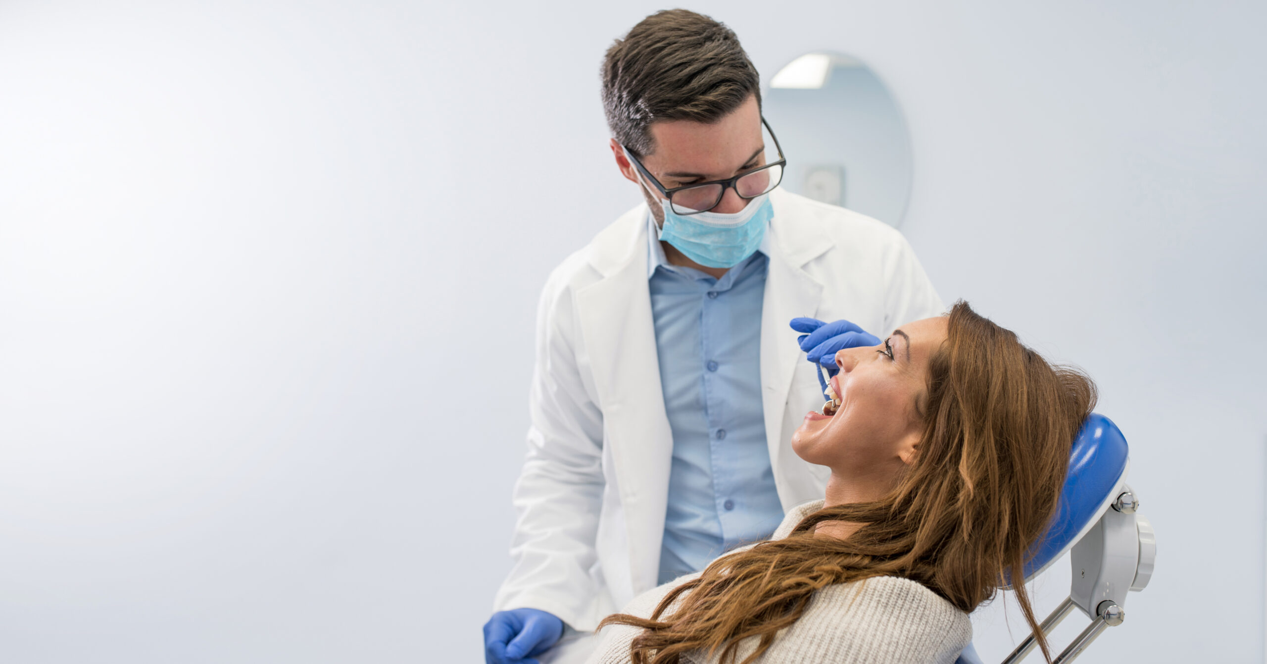 High angle view of dentist examining woman with dental equipments
