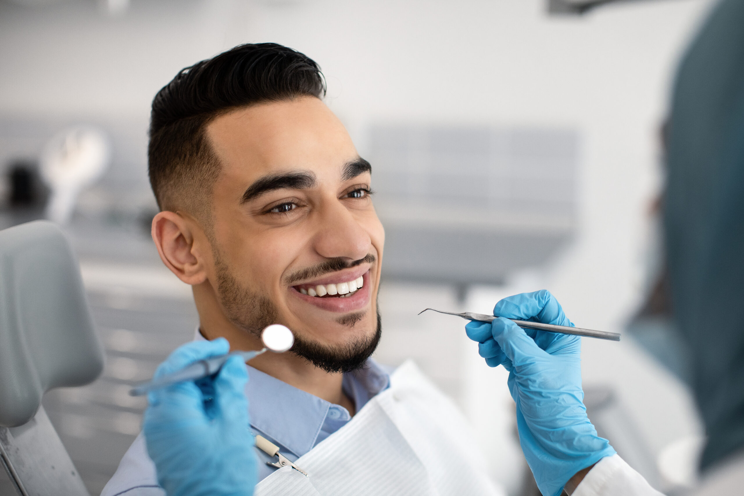 Closeup Of Happy Middle Eastern Male Patient Getting Dental Treatment In Modern Clinic, Islamic Dentist Woman Examining Teeth Of Arab Man With Sterile Tools In Stomatological Cabinet, Cropped Shot