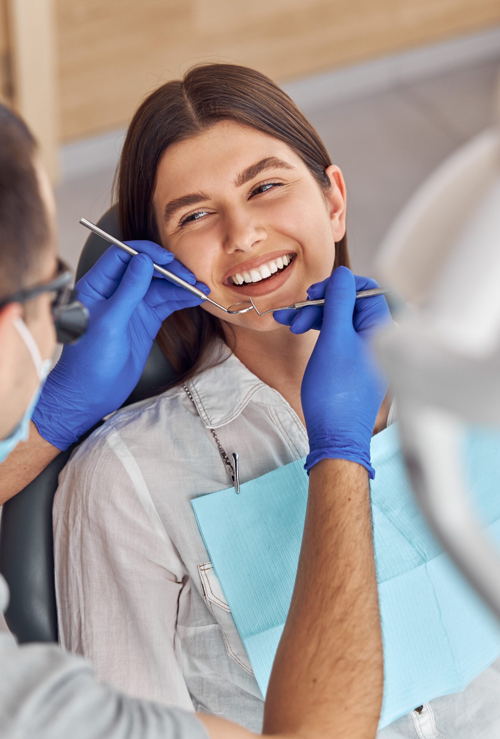 Cheerful positive dentist and client in dentistry. They look at each other and smile. Female client sit in chair