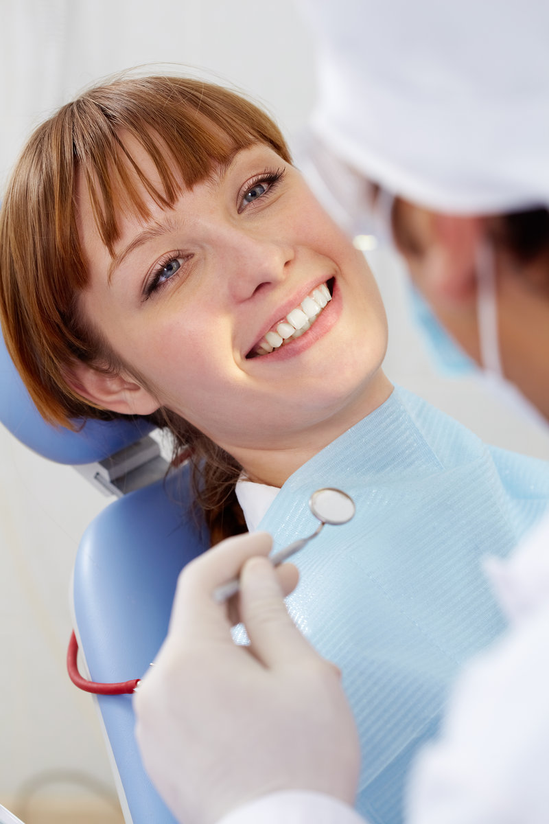 Image of smiling patient looking at the dentist with mirror