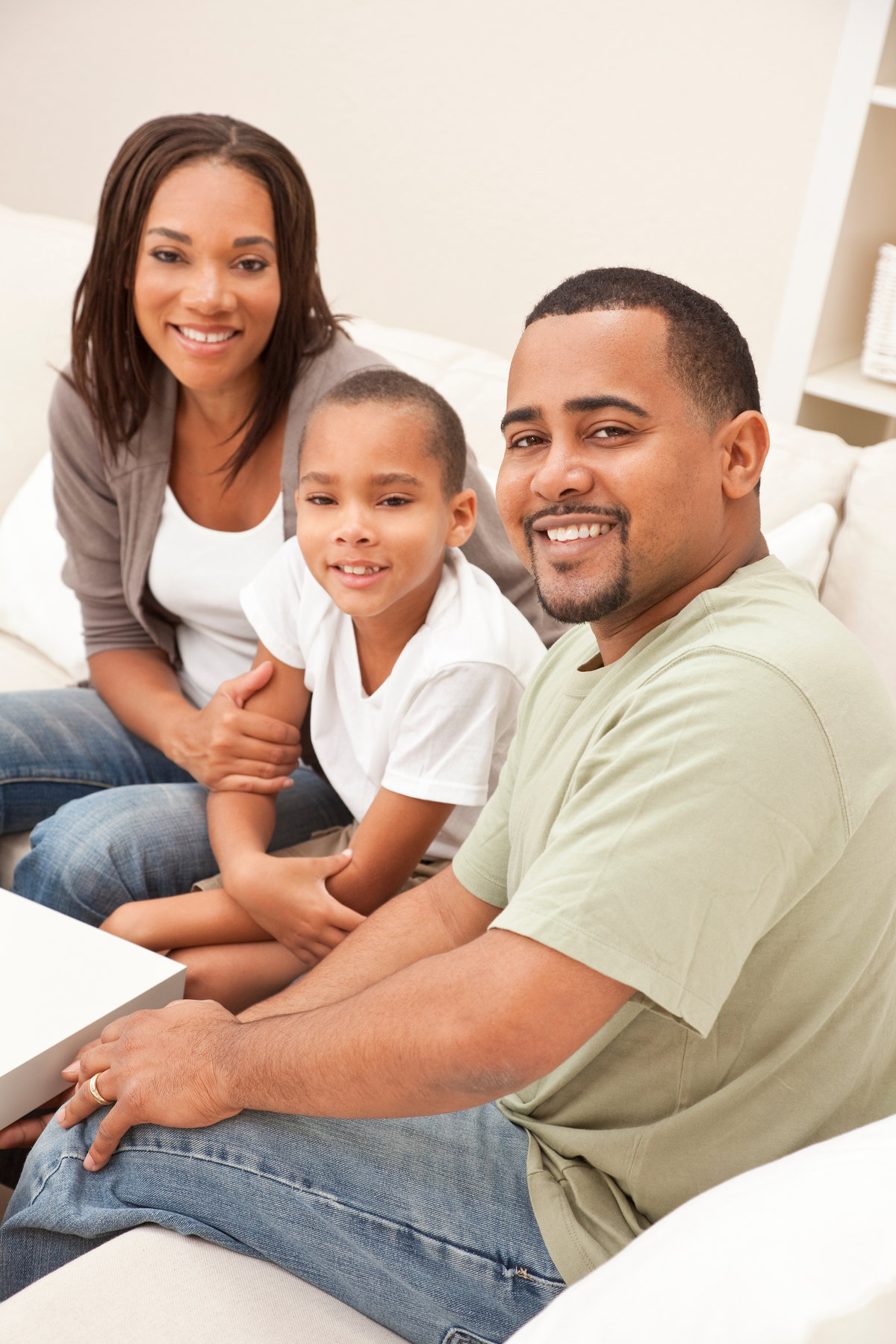 A happy African American man, woman and boy, father, mother and son, family sitting together at home