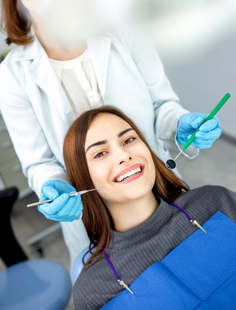 A woman patient sits in a dental chair at a dentist doctor's appointment. A girl with a beautiful smile and white even teeth.