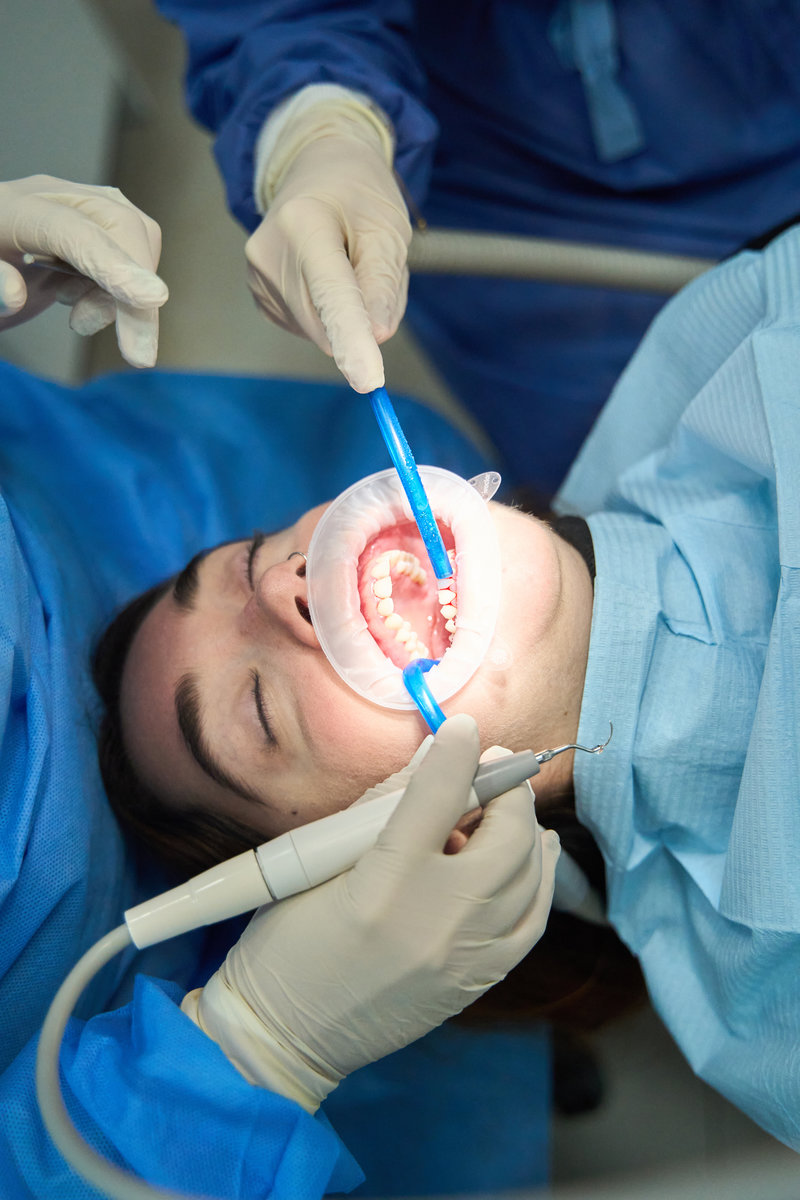 Dental team working on a patient's mouth using specialized tools, performing a dental procedure