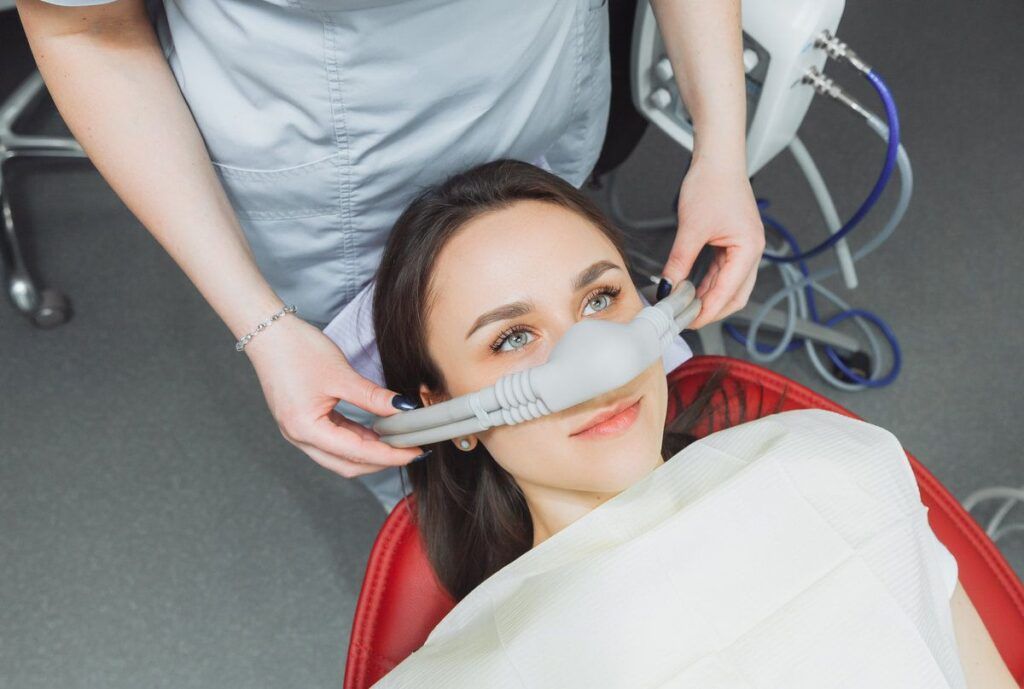 dentist puts inhalation sedative mask on his patient.