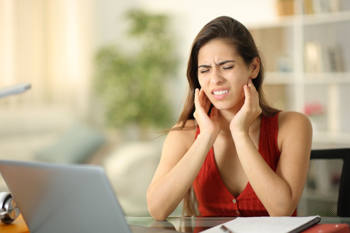 Young woman holding her jaw in pain due to a dental emergency